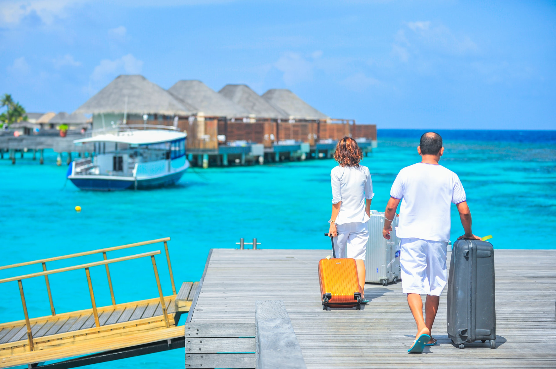 A couple walking along a jetty towards overwater villas
