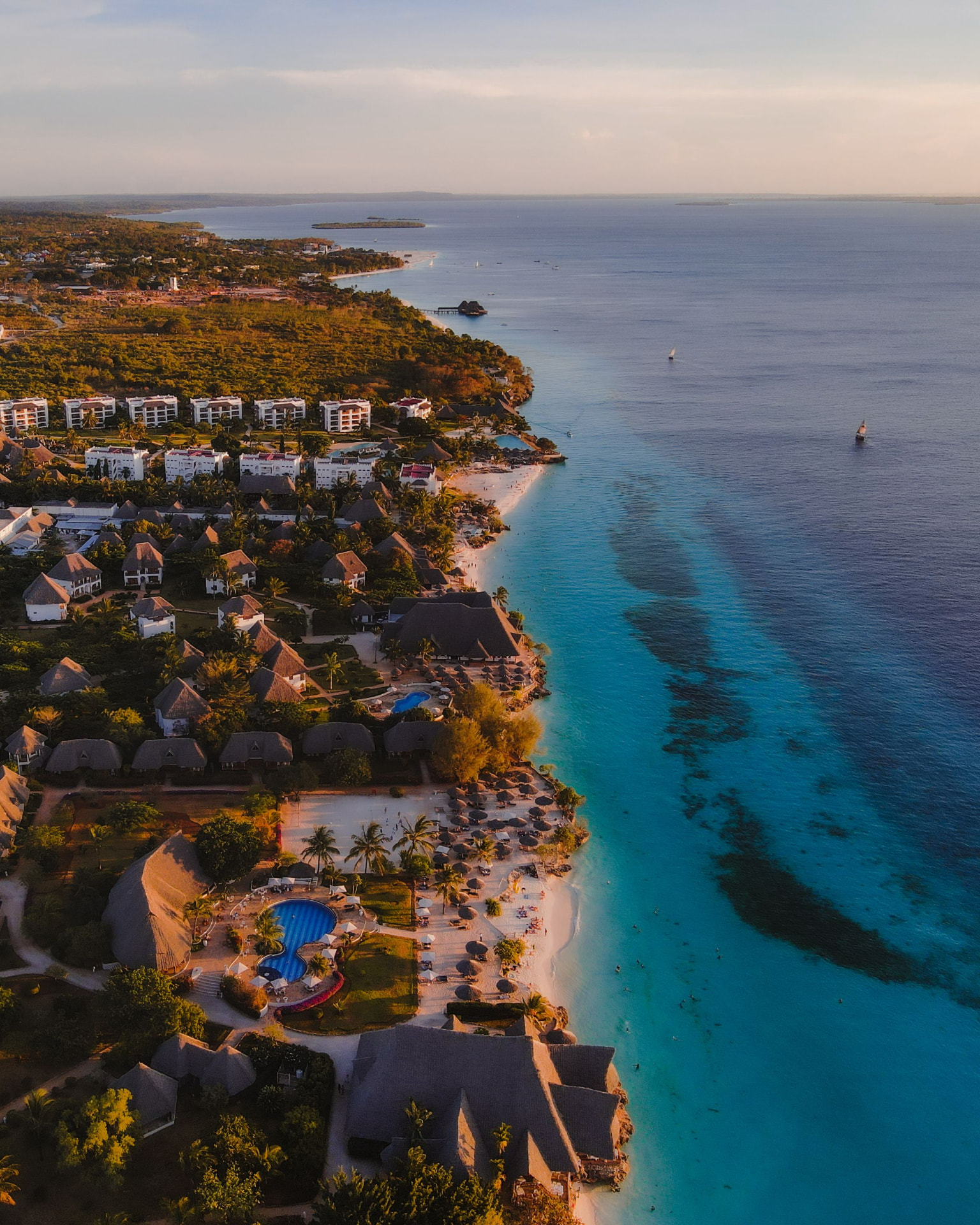 Aerial view of a tropical beach resort coastline at golden hour